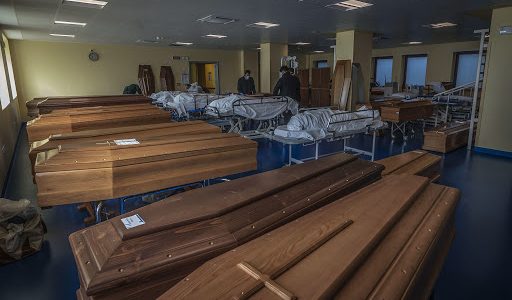 Funcionários de uma funerária preparam caixões em Bérgamo.